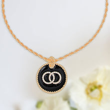 Load image into Gallery viewer, Black epoxy pendant with interlocking rhinestone rings on a gold-tone rope chain.